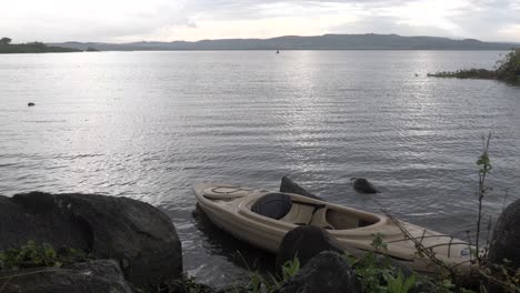 un kayak atracado en las orillas del lago victoria en el sol de la mañana temprano