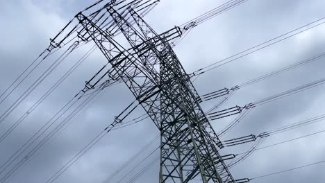 Bottom-up-shot-of-power-pole,-electricity-pylon-against-dramatic-cloudy-sky-in-rural-area