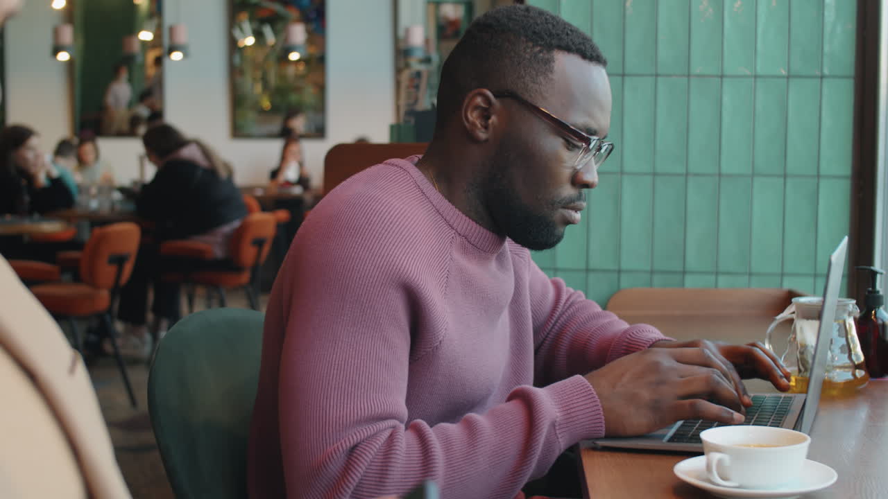 Black Businessman Working on Laptop in Cafe