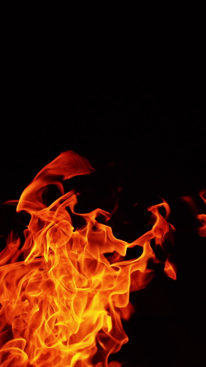 Fiamma rovente che si alza nell'aria. Grande falò acceso di notte. Primo piano. Video verticale