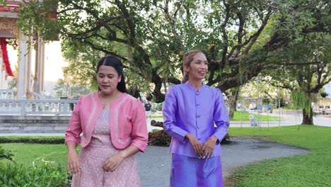 two women in traditional thai attire at a temple