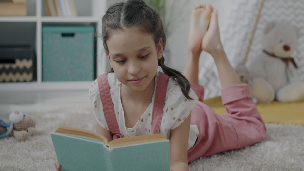 Niña leyendo un libro en el suelo