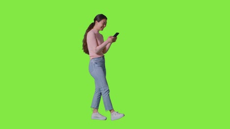 Foto-De-Estudio-Completa-De-Una-Mujer-Sonriendo-Y-Riéndose-De-Un-Mensaje-O-Contenido-En-Un-Teléfono-Móvil-Contra-Una-Pantalla-Verde-1