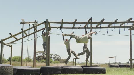 Fit-diverse-group-of-soldiers-using-hanging-rope-and-rings-on-army-obstacle-course-in-the-sun