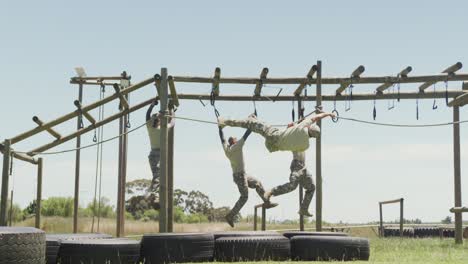 un grupo diverso de soldados usando cuerda colgante y anillos en el curso de obstáculos del ejército en el sol