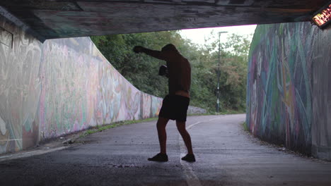 wide shot of young attract man boxing in underpass, in slow motion