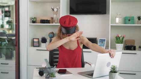 la mujer se sienta en la oficina y habla en la computadora portátil a través de una cámara web, cubriendo su cara para evitar ser reconocida
