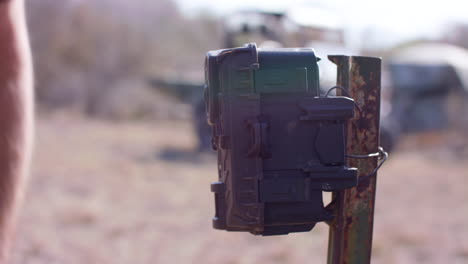 man putting a trail camera on a post