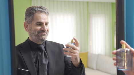 hombre de negocios carismático en traje mirándose a sí mismo en el espejo y rociando perfume.