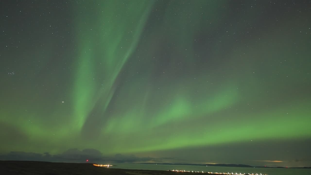 un video en lapso de tiempo de las encantadoras luces del norte bailando sobre un fiordo tranquilo en una oscura noche de invierno