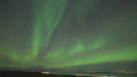 Ein-Zeitraffervideo-Der-Bezaubernden-Nordlichter,-Die-In-Einer-Dunklen-Winternacht-über-Einem-Ruhigen-Fjord-Tanzen