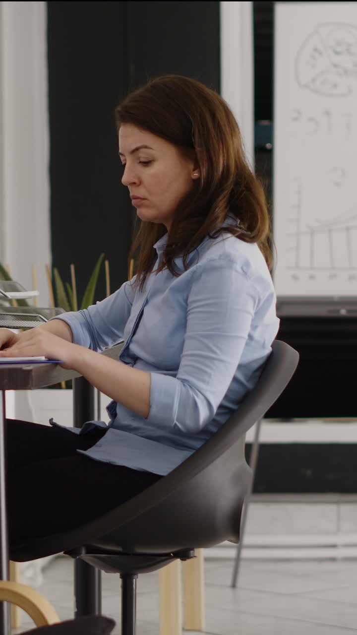 Video verticale: donna d'affari che controlla un piano di investimento al computer