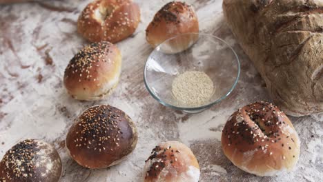 close up of rolls, bread, flour and rolling pin on table in bakery kitchen, slow motion