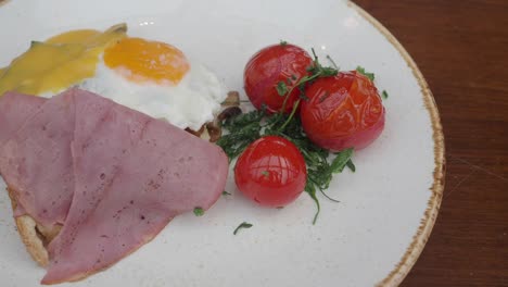 gourmet breakfast plate with fried egg, ham, and roasted tomatoes