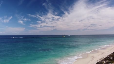 Aerial-view-over-Eden-Beach,-Perth-with-fisherman-and-drilling-platform-in-background