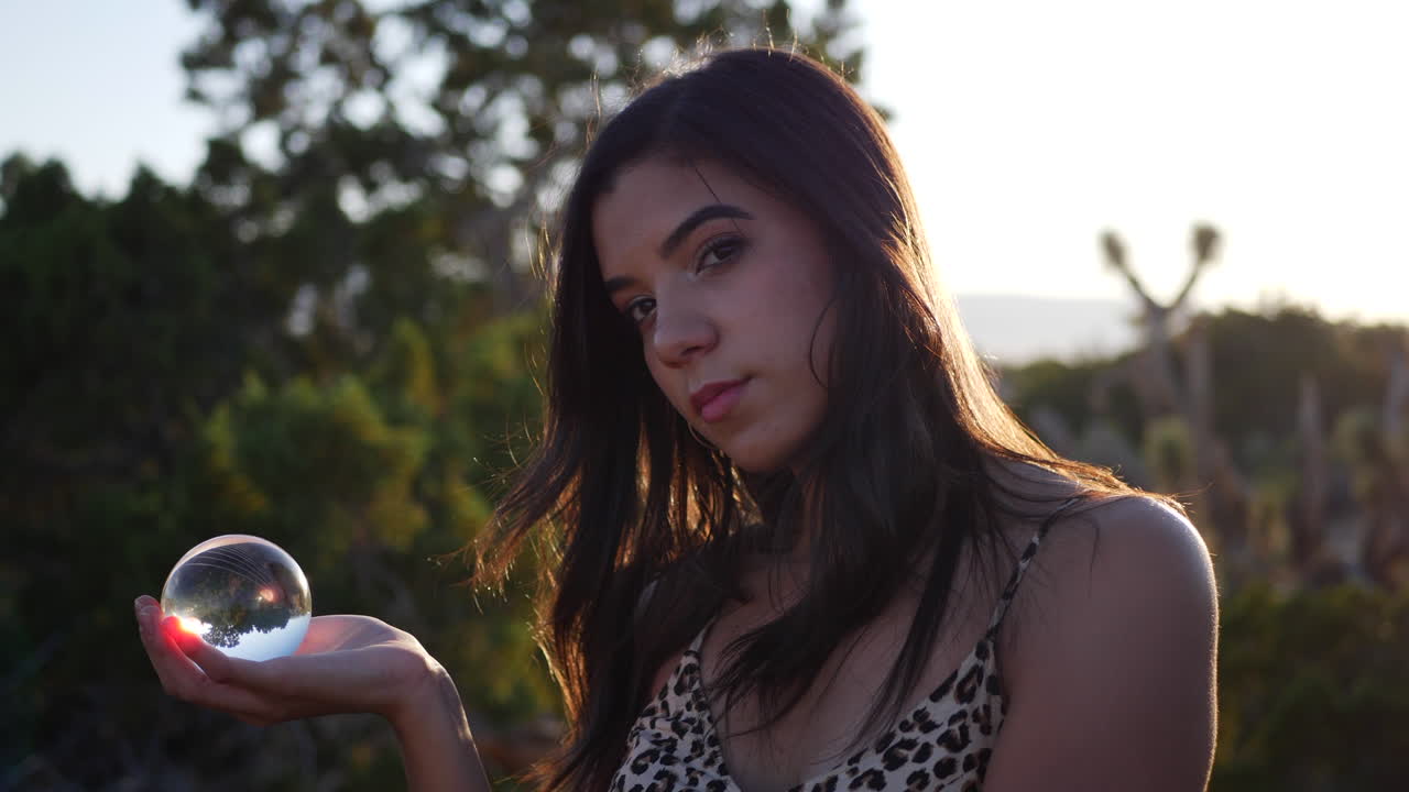 A gorgeous dreamy hispanic woman in a mystical fantasy world with a magical crystal ball and a serious stare SLOW MOTION