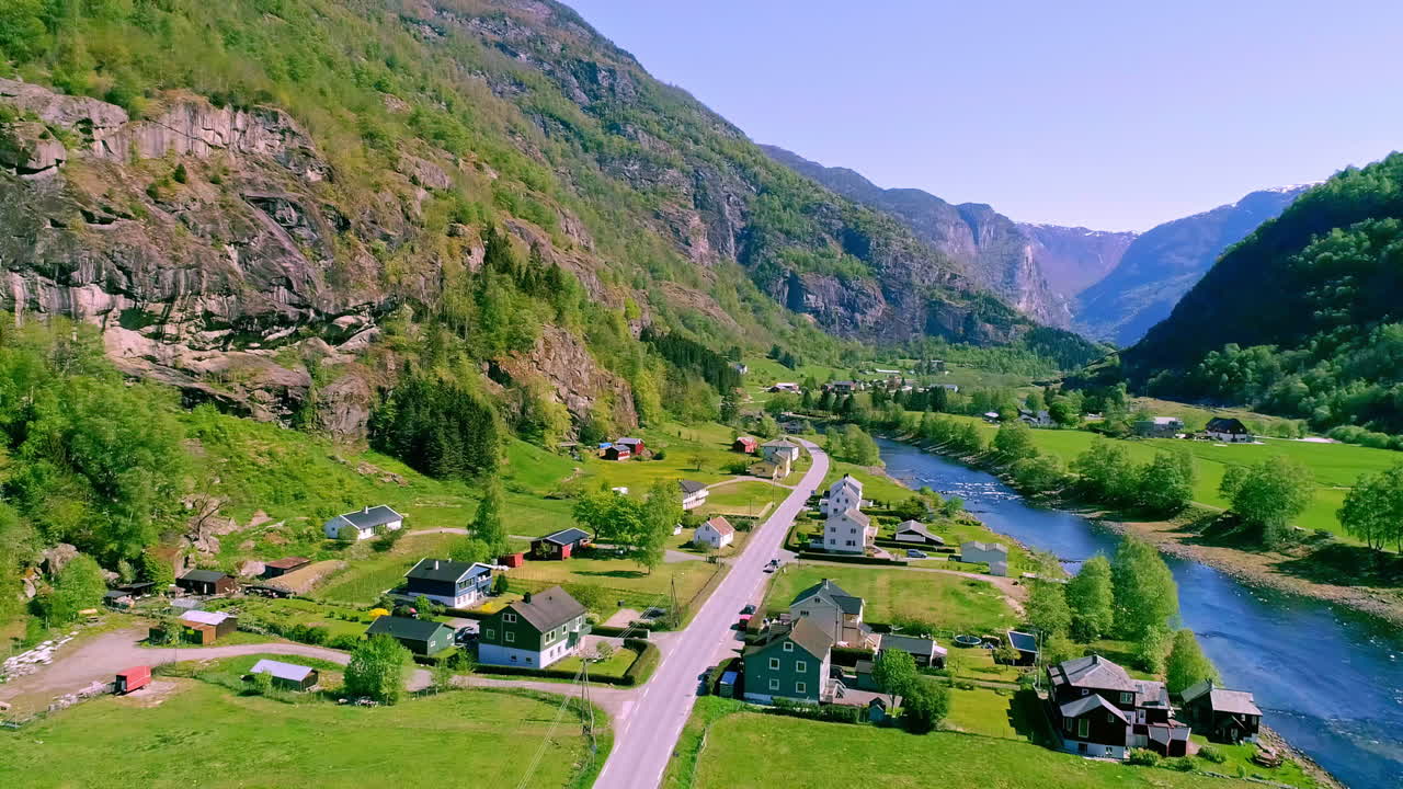 pueblo rural a lo largo de las orillas del río con paisaje de montaña en segundo plano.