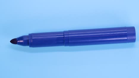 blue marker pen rotating on blue surface background, macro shot close up view detail