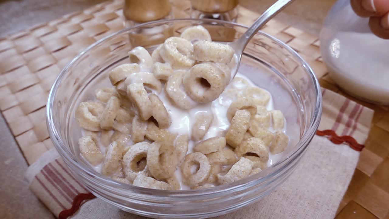 copos de avena crujientes en un tazón para un delicioso desayuno matutino con leche. cámara lenta con toma de seguimiento de rotación.