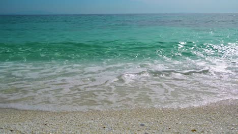 Kristallklare-Türkisfarbene-Meereswellen-Plätschern-Am-Marmorstrand,-Klarer-Blauer-Himmel-Im-Hintergrund,-Weißer-Strand,-Insel-Thassos,-Griechenland