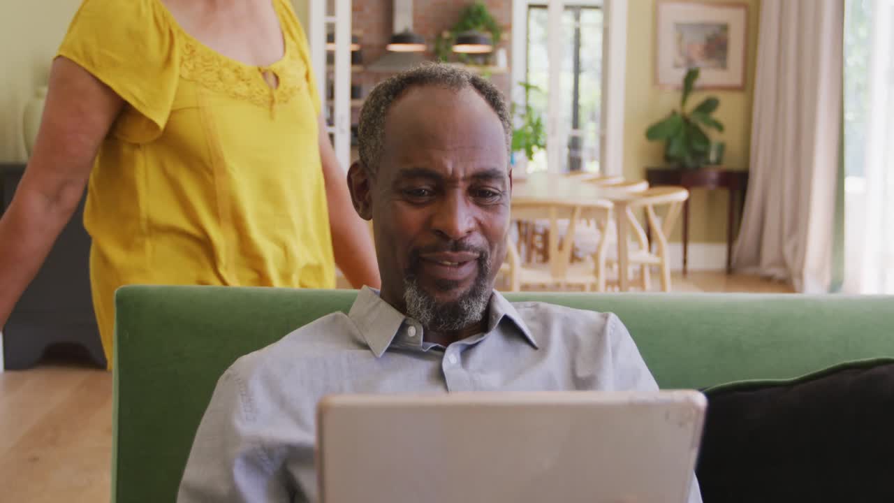 Senior African American husband and mixed race wife spending time and working at home