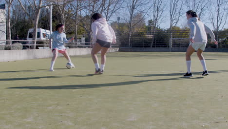 active teenage girls playing football at open air pitch