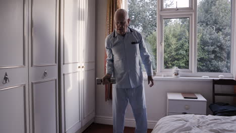 elderly man exercising with a dumbbell in his bedroom