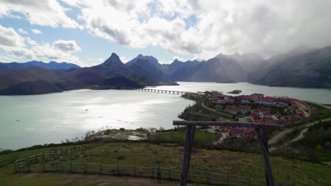 fast aerial dolly shot with a family swinging their child on the swing at the viewpoint in riaño, a village in león, spain on the shore of a large reservoir in the cantabrian mountains