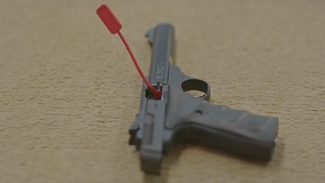 hand removing chamber flag from pistol and revealing an empty chamber