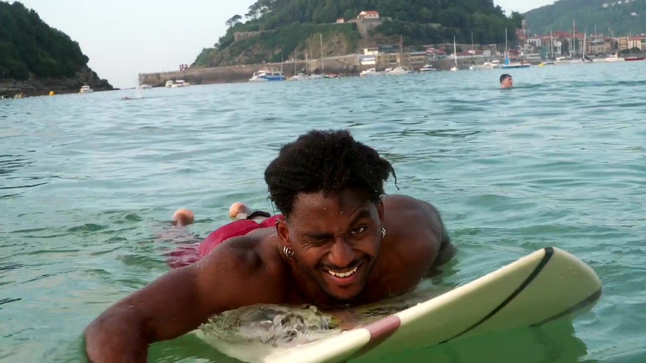 Giovane uomo che pagaia sulla tavola da surf nel mare