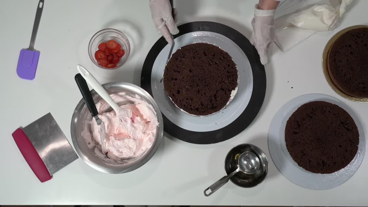 크림으로 인 케이크의 을 조심스럽게 만지기 위해 아이싱 스파라를 사용하는 베이커의 앞.