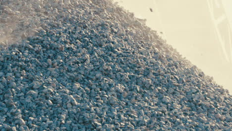 sunlight-on-rock-pile,-rocks-falling-and-tumbling-down,-sunny-gravel-quarry-closeup-in-slowmotion