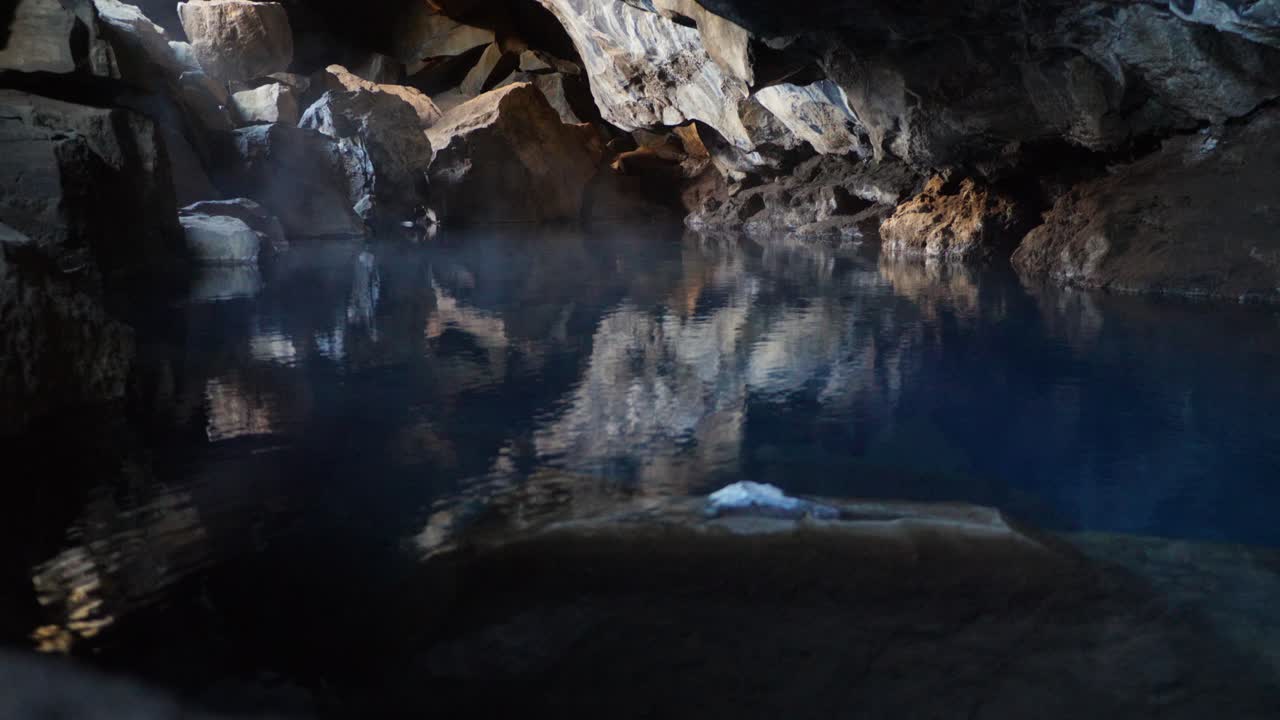 아이슬란드의 무보르기르 (dimmuborgir) 에 있는 안개가 가득한 화산 동굴이 조용한 물 속에 반사되어 있다.