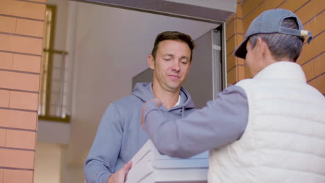 man receiving pizzas from cheerful courier who has a clipboard on her hands