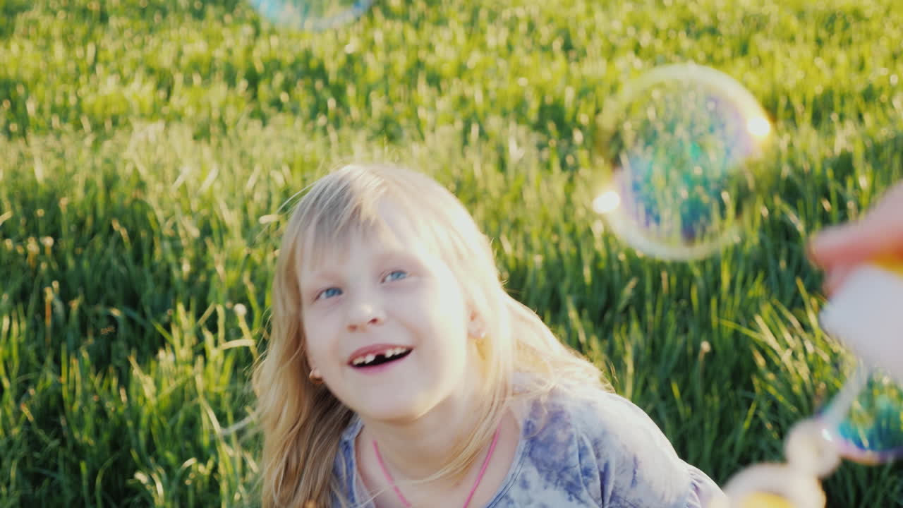 una chica alegre atrapa pompas de jabón y sus dientes de leche se cayeron en un video en cámara lenta de 4k