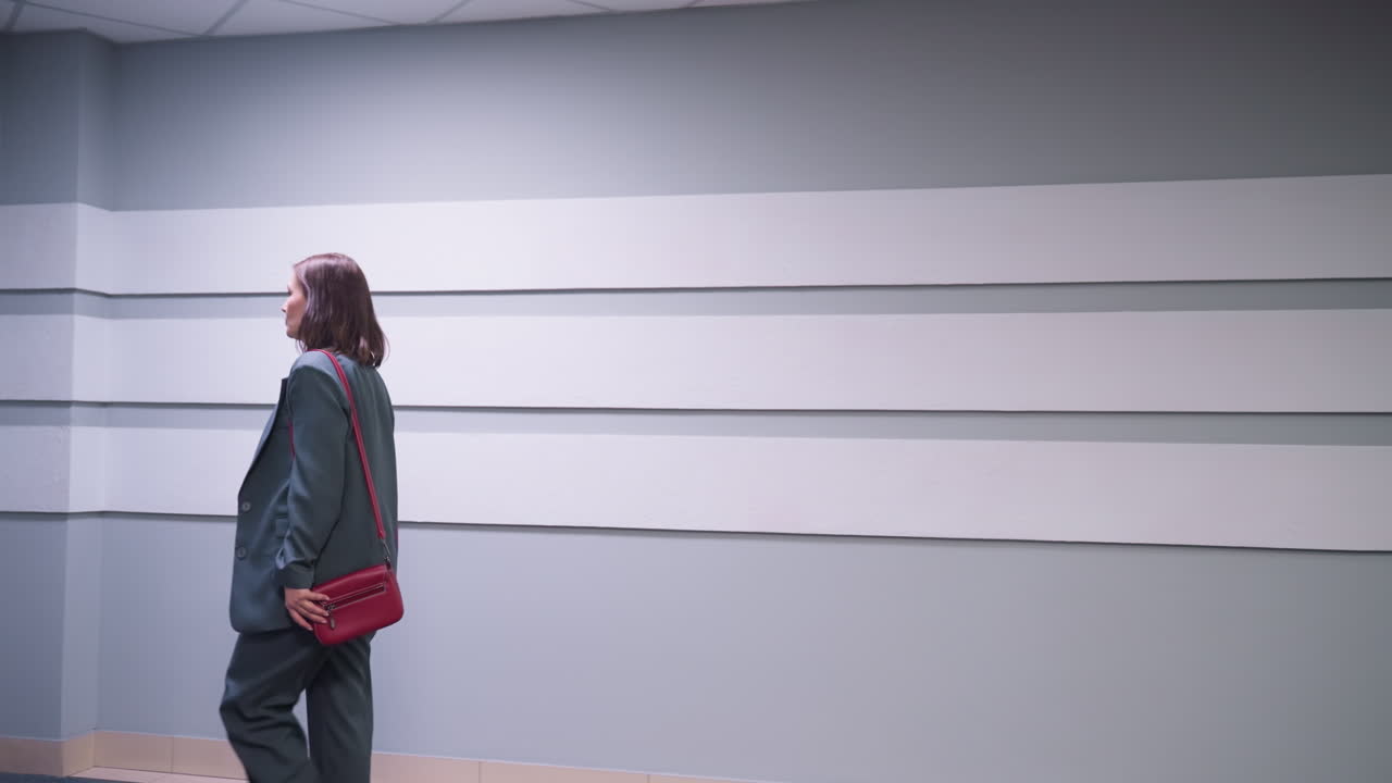 Modern office hallway with minimalist wall design, textured panels, and distant lounge area featuring grey couches and corporate doors, creating a professional and contemporary workspace atmosphere