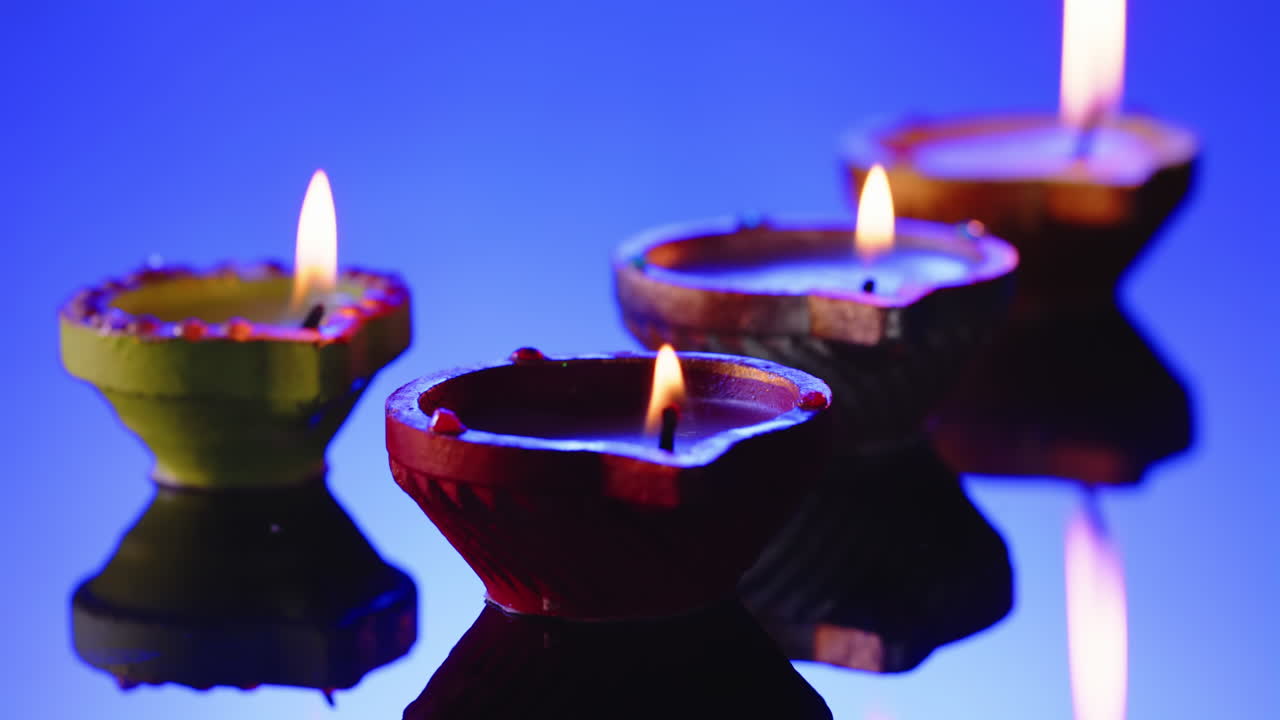 Primo piano di candele accese in fila che celebrano il Diwali su sfondo blu