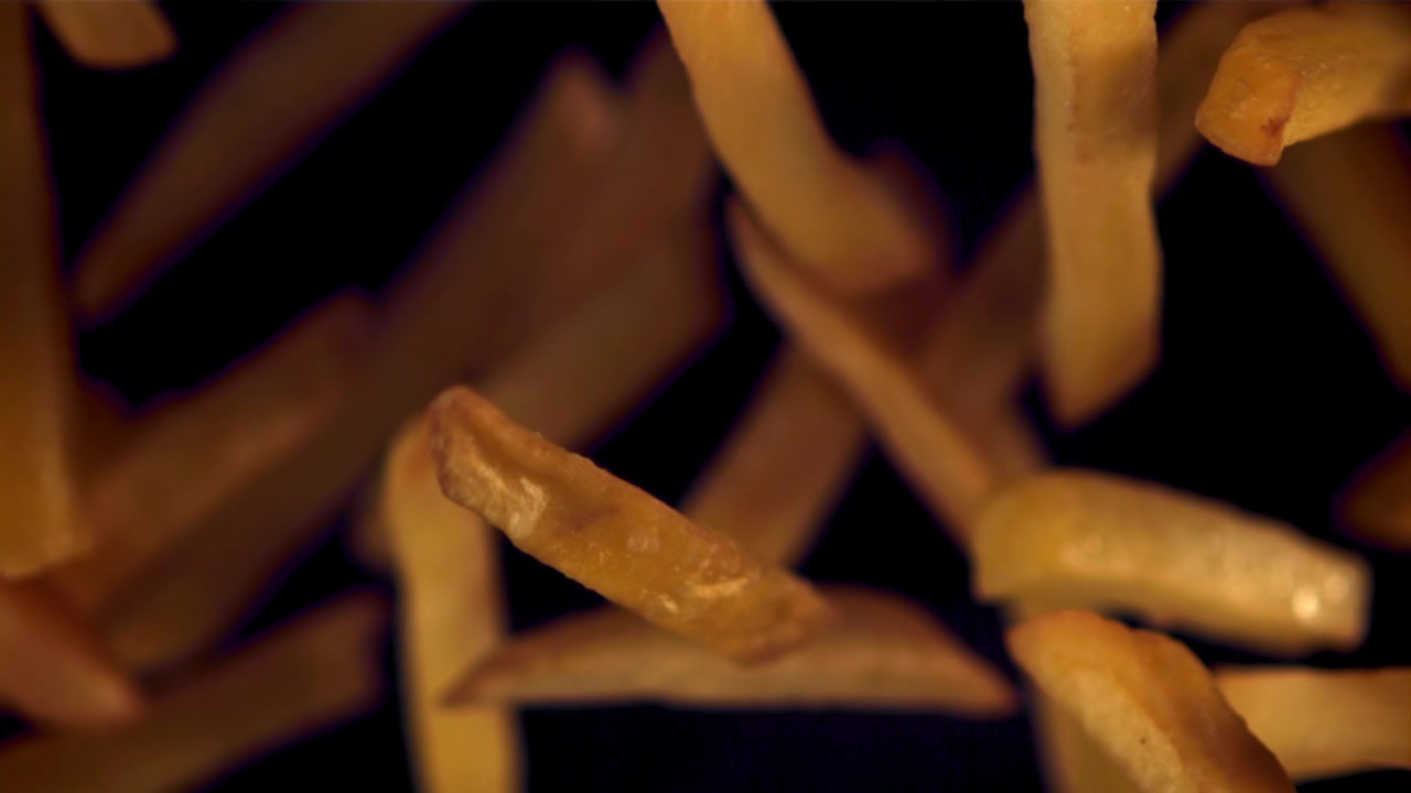 Golden French Fries Coming into Focus on a Black Background