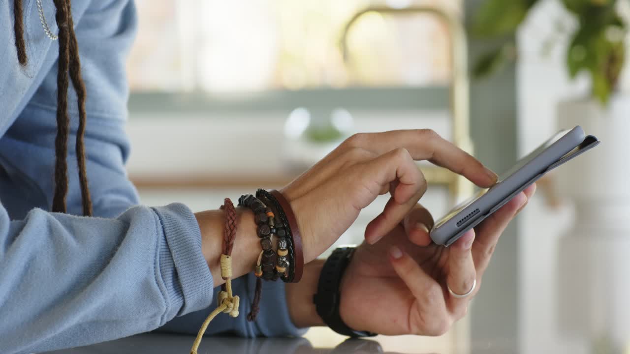 Hands lifting smartphone from wooden tabletop, tapping and swiping screen while scrolling feed