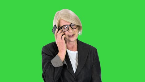 senior businesswoman making a call while walking on a green screen, chroma key