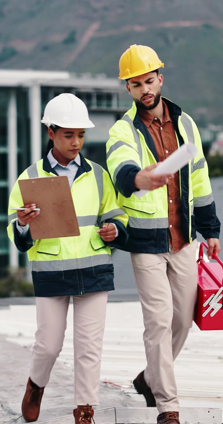 Construction Engineers Walking and Discussing Blueprints on Site