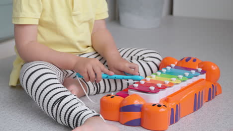 close up of little girl's hands playing music on toy xylophone