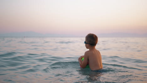 Child-taking-ball-to-water-and-then-floating-on-it-in-the-sea