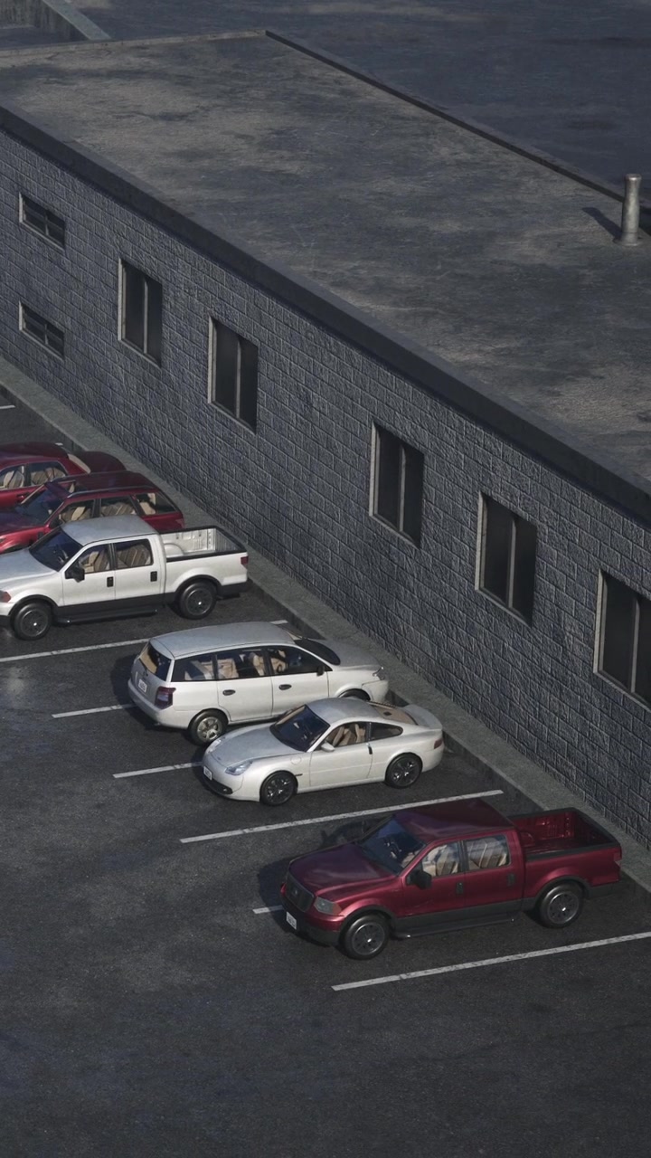Biler parkeret på en parkeringsplads nær en grå bygning ved middagstid.