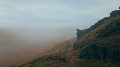 aerial drone view of morning mists moving slowly over the rugged pennine hills, on a foggy morning, golden hills and beautiful rocky cliffs and moorlands