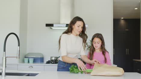 Feliz-Madre-E-Hija-Caucásicas-Desempacando-Comestibles-En-La-Cocina