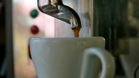 Coffee-drizzles-down-into-white-porcelain-teacup,-slow-motion-closeup-orbit