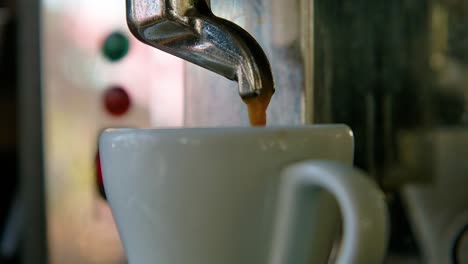 coffee drizzles down into white porcelain teacup, slow motion closeup orbit