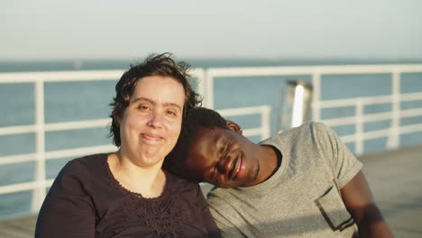 portrait of happy couple using wheelchairs sitting on bridge