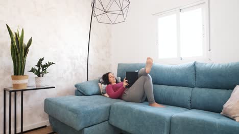 young woman relaxing on the sofa at home reading a book